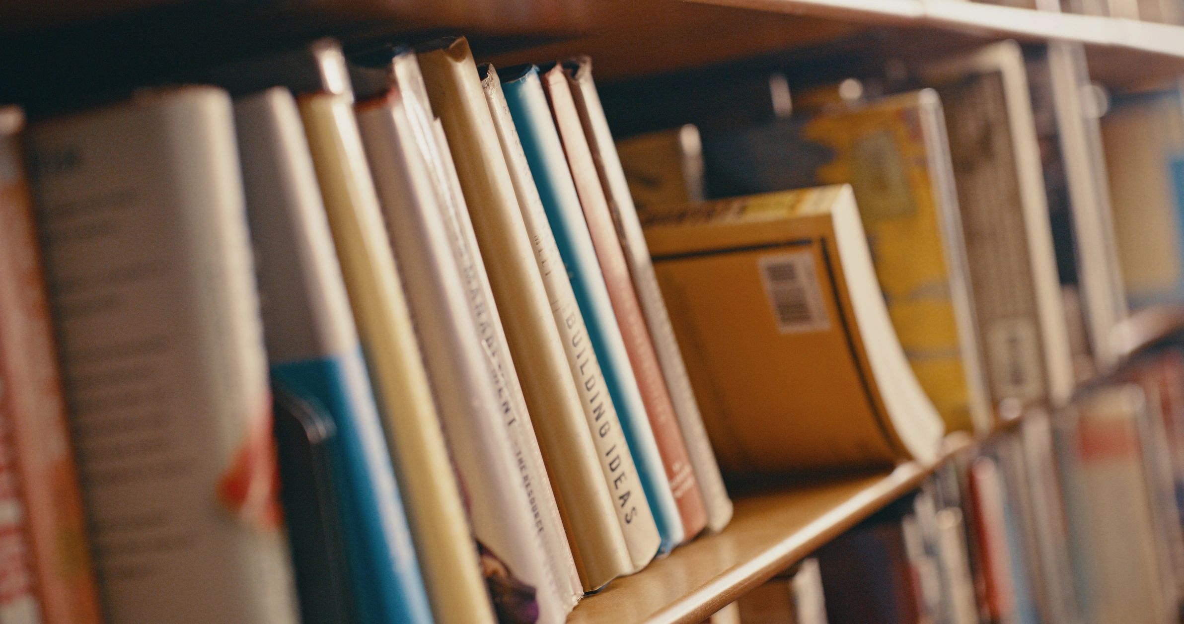 Close-up of books neatly arranged on a wooden shelf.